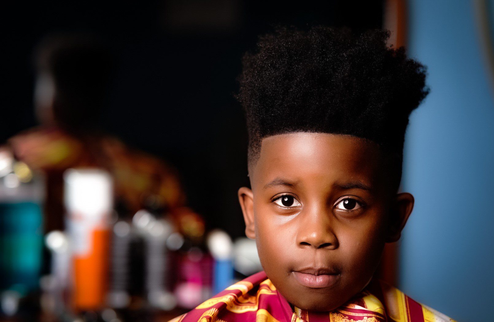 A young boy with an afro is posing for the camera.