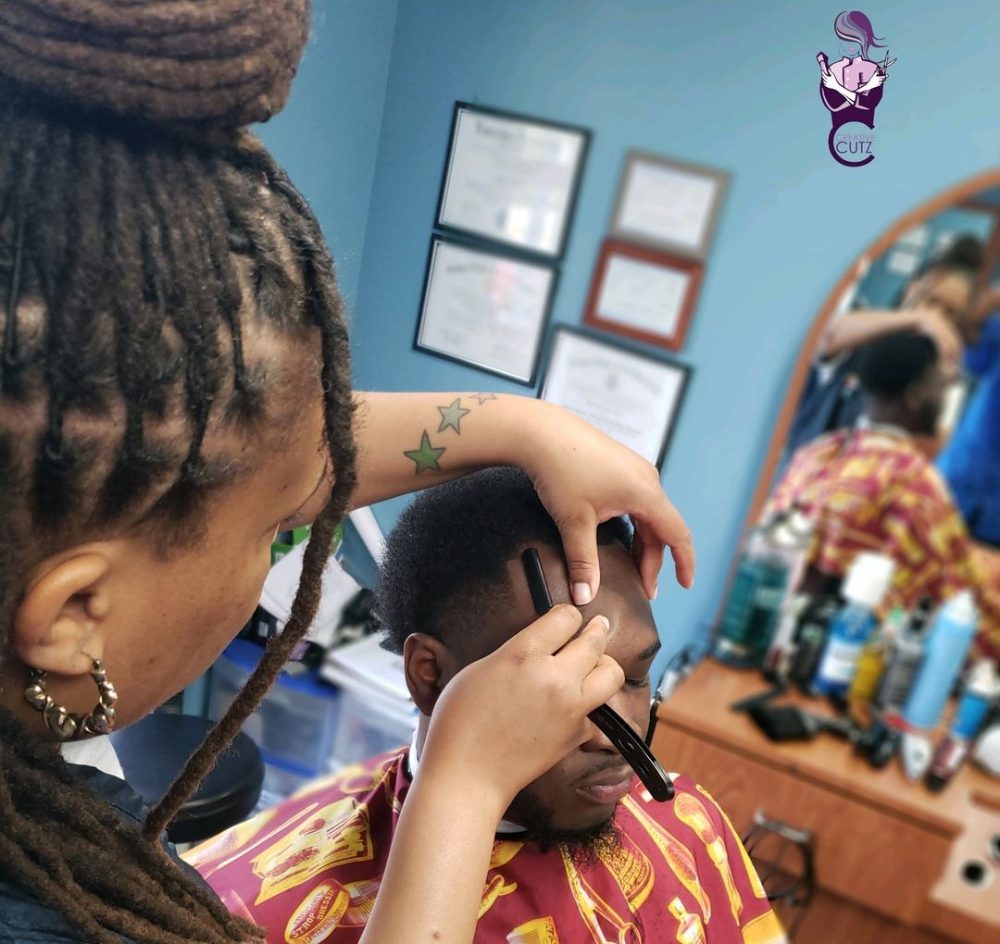 A woman is cutting another person 's hair.
